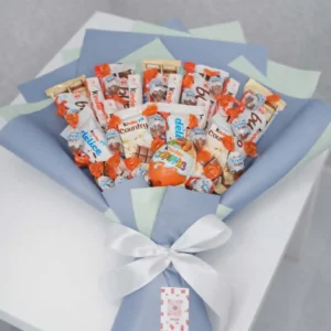Handcrafted sweet bouquet featuring Kinder Surprise eggs, Kinder Bueno, and Delice bars wrapped in pastel blue and mint paper with a white satin ribbon.
