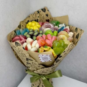 Hand-held edible bouquet made of colorful gummy and jelly candies wrapped in heart-printed kraft paper with a green ribbon