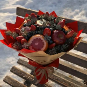 Rustic edible bouquet made of fresh strawberries, sliced grapefruit, red apples, and pine branches wrapped in brown kraft paper