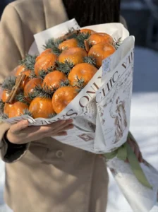 fancy-fruit-winter-tangerine-cinnamon-bouquet Rustic winter edible bouquet made of fresh tangerines, pine branches, and candy canes wrapped in printed brown kraft paper