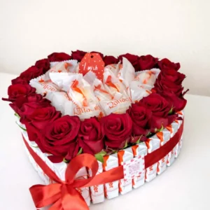 Large heart-shaped gift arrangement framed by Kinder chocolate bars, filled with fresh red roses and Raffaello candies, tied with a red ribbon