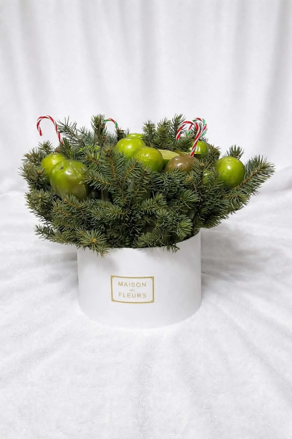 Sophisticated Armenian gifts for her: tangerine bouquet in a white hat box with natural evergreen boughs and festive candy canes.