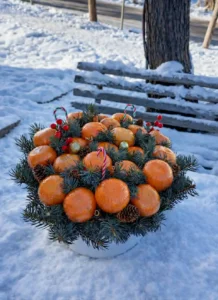 Luxury Christmas tangerine gift box: edible bouquet of fresh tangerines, pine branches, cones, red berries, candy canes, and ornaments