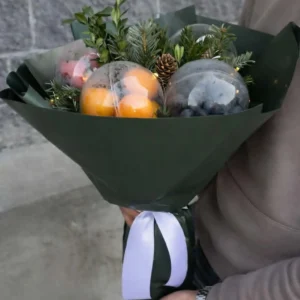 premium-edible-gift-bouquet-tangerines-nuts-pine abovyan Premium winter edible gifts arrangement in a handheld bouquet of tangerines, nuts, and evergreen boughs in dark green paper wrapping.