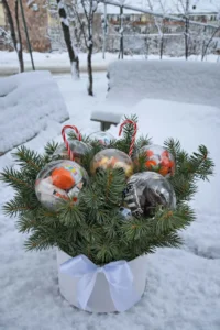Premium edible gifts concept with Kinder Bueno and M&Ms inside transparent spheres surrounded by fresh pine .