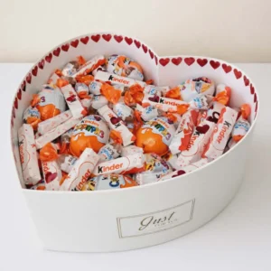 Large 40cm white heart-shaped hat box overflowing with assorted Kinder chocolates: Kinder Surprise, Bueno, bars, Schoko-Bons, adorned with red hearts