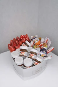 A 25cm white heart-shaped gift box filled with fresh red strawberries, mini Nutella jars, Kinder Surprise eggs, and Kinder chocolate bars.